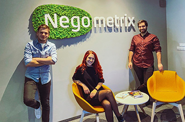 Three people in a office environment with sign Negometrix on green background